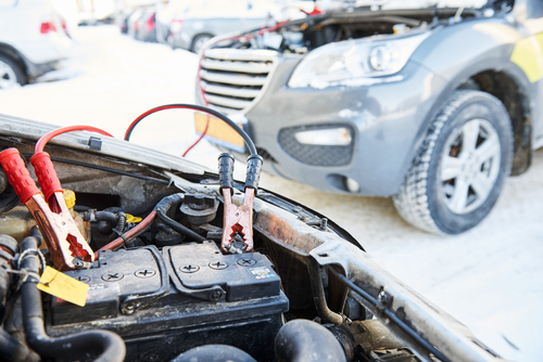 Charging automobile discharged battery by booster jumper cables at winter winter road assistance. Auto engine starting problem. Car battery discharged. Charging by booster jumper cables